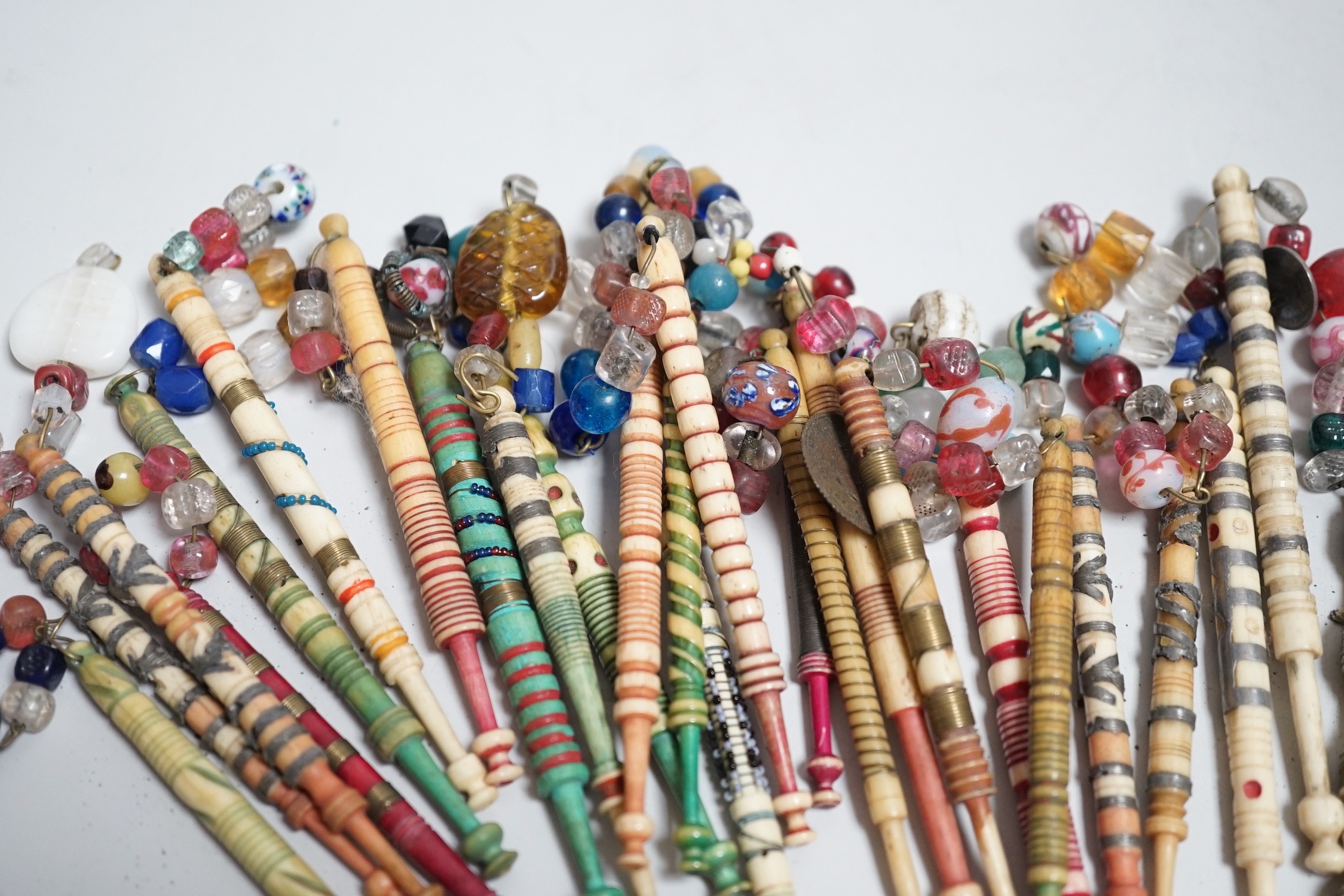 Twenty one 19th century stained and turned bone lace bobbins with glass bead tops and thirteen ornate bone and metal decorated lace bobbins with bead tops (35)